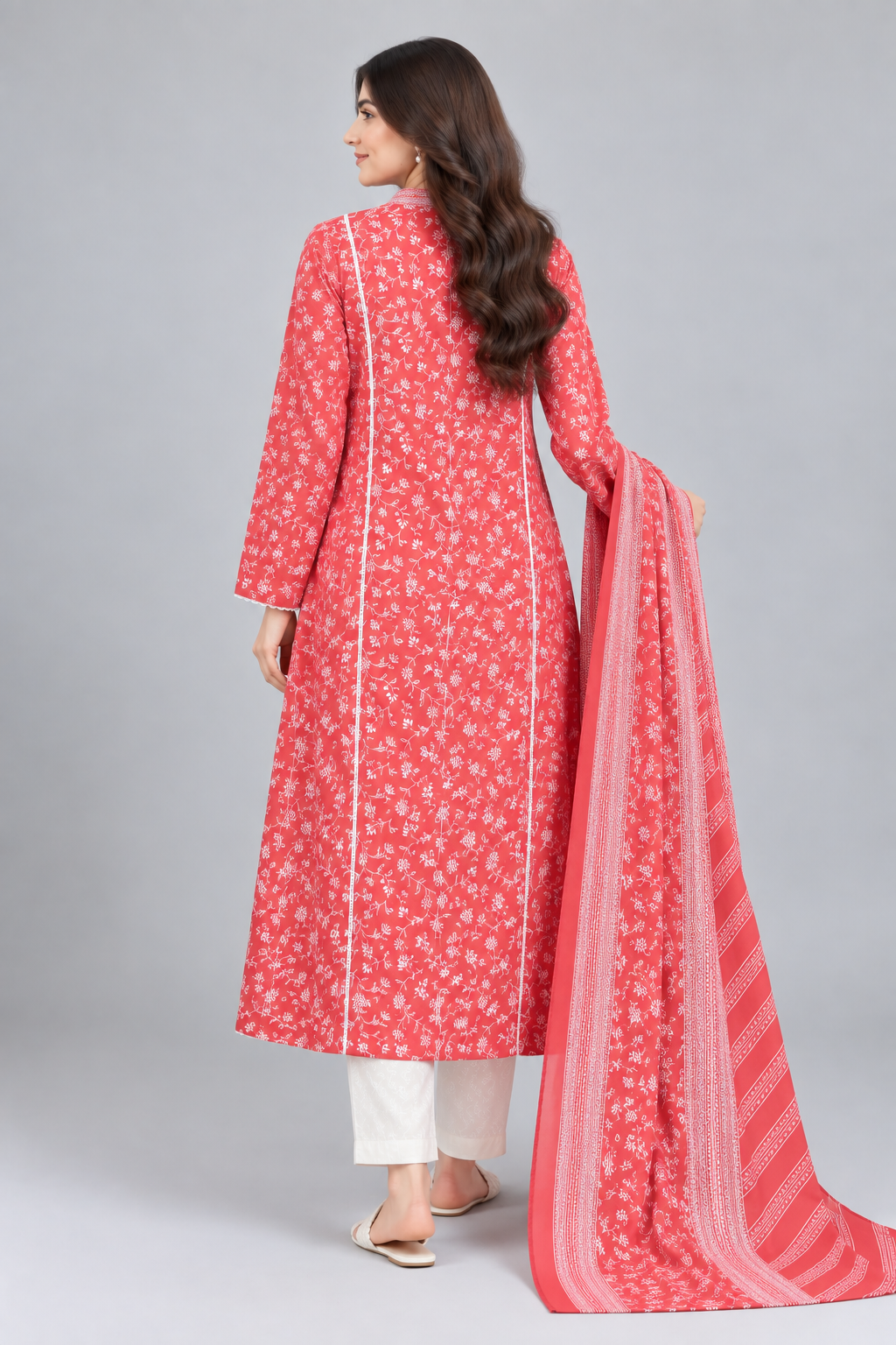 Back view of a woman wearing a coral pink printed long shirt with white floral pattern, white trousers and matching dupatta.